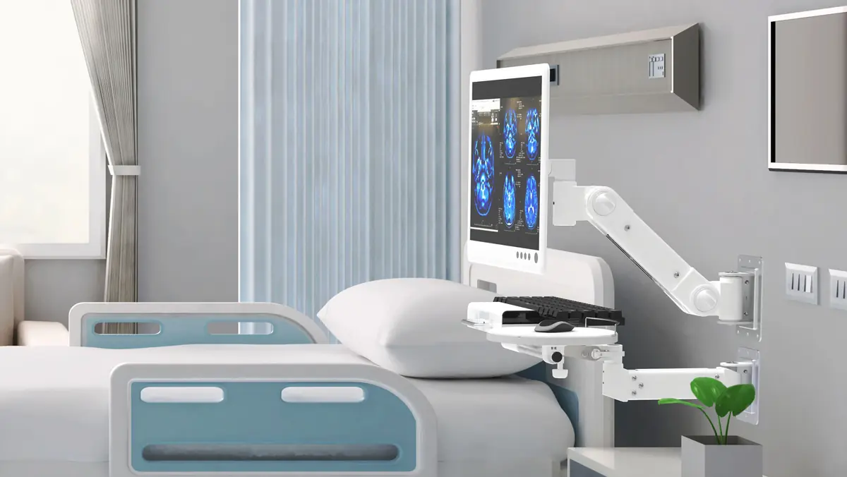 Monitor arm mounted beside a hospital bed